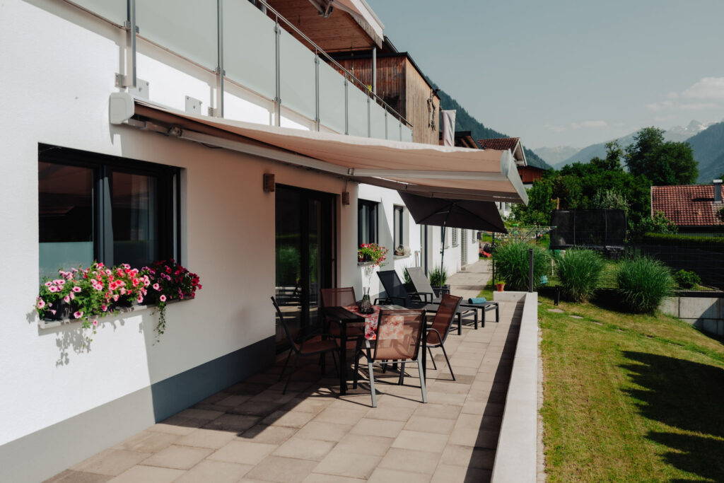 Helle moderne Terrasse mit Sonnenmarkise und Terrassenmöbeln