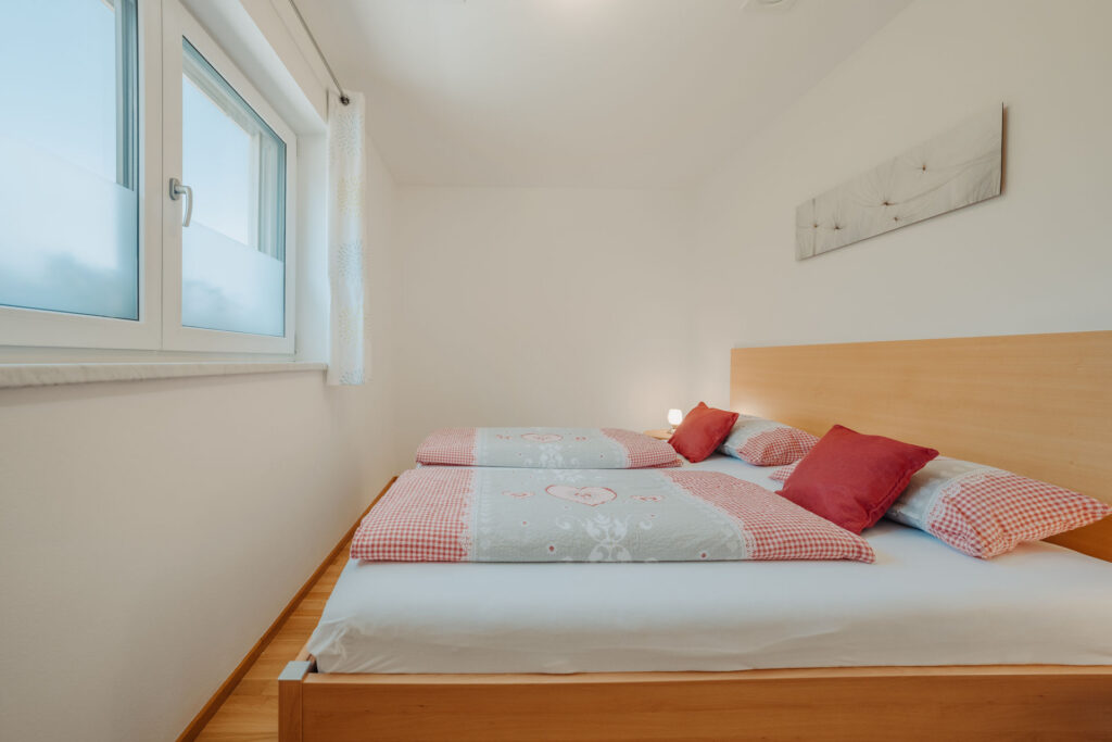 modernes helles Schafzimmer mit Holzbett ausgerichtet mit Blickrichtung zum Fenster