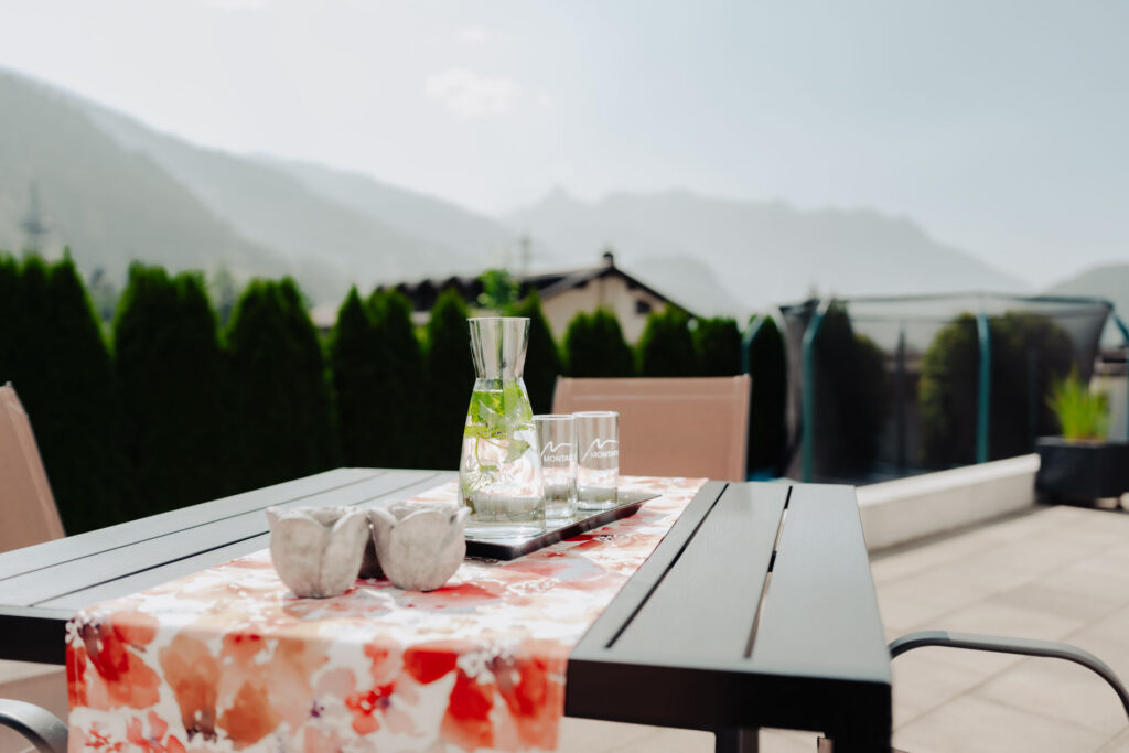 Ausblick von Terrassentisch auf Bergwelt bei Sonnenschein
