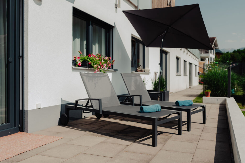 Helle moderne Terrasse mit Sonnenschirm und Liegestühlen